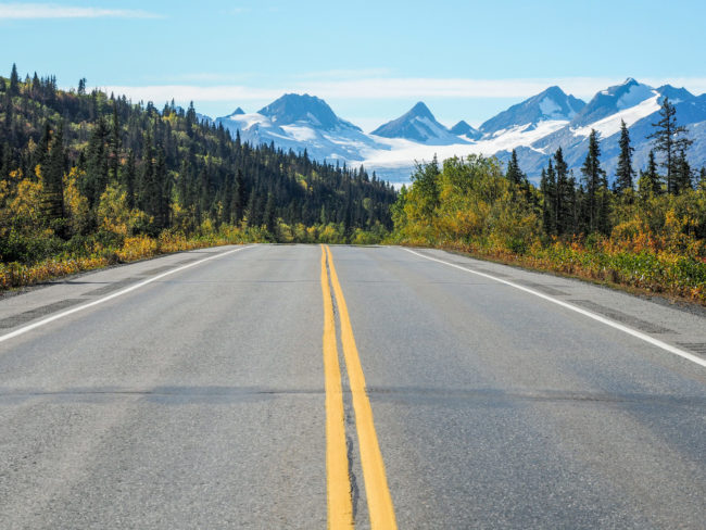 asphaltstrasse-mit-gelben-linien-und-dem-worthington-gletscher-in-alaska-scaled-1